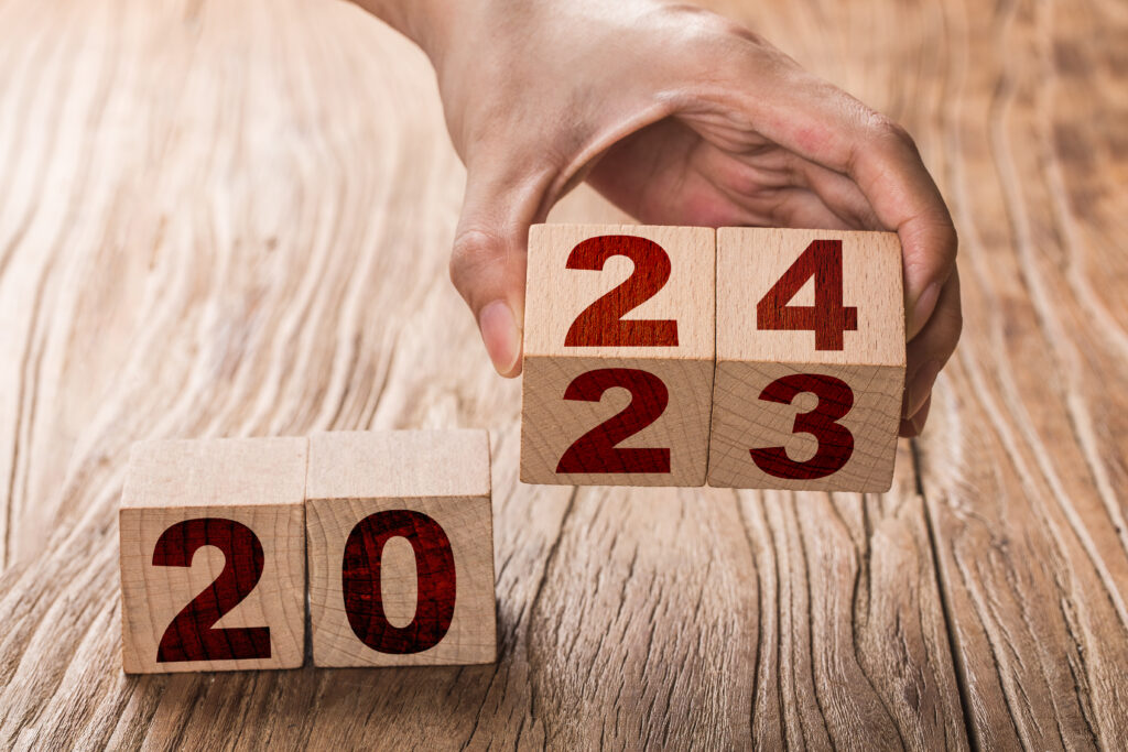sobre uma superfície, dois blocos de madeira com um algarismo cada um formam o número 20. O lado, uma mão segura outros dois blocos que formam o número 24