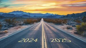 foto de uma estrada no meio de uma planície árida com pouca vegetação, sob o pôr do sol. no asfalto de cada faixa da estrada, a pintura do texto "2024" e "2025"